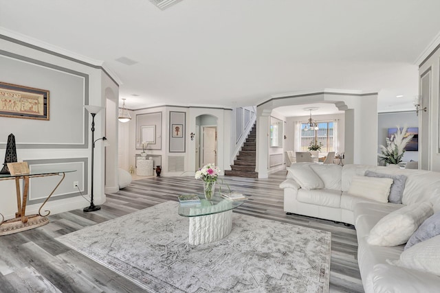 living room featuring ornate columns, ornamental molding, an inviting chandelier, and hardwood / wood-style floors