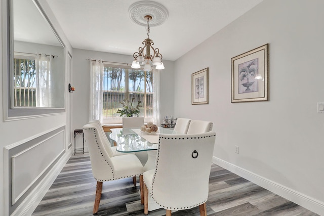 dining space with dark hardwood / wood-style flooring, an inviting chandelier, and a wealth of natural light