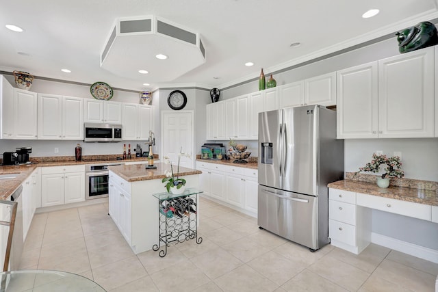 kitchen featuring a center island with sink, light tile patterned floors, appliances with stainless steel finishes, white cabinetry, and light stone countertops