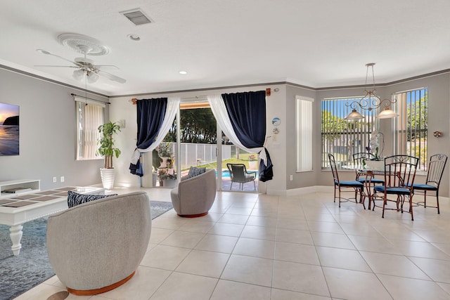 tiled living room featuring crown molding and ceiling fan with notable chandelier