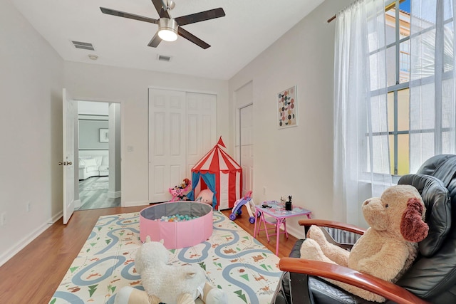 playroom with a healthy amount of sunlight, wood-type flooring, and ceiling fan