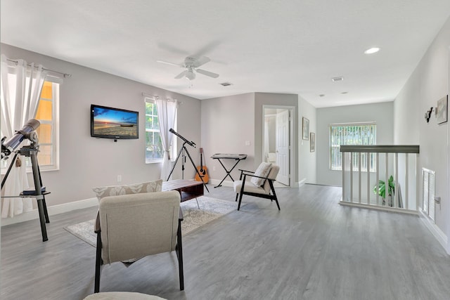 living area with ceiling fan, a healthy amount of sunlight, and light wood-type flooring