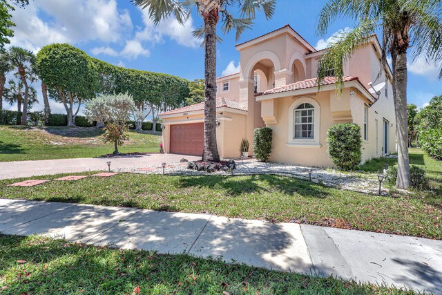 mediterranean / spanish-style house with a garage and a front lawn