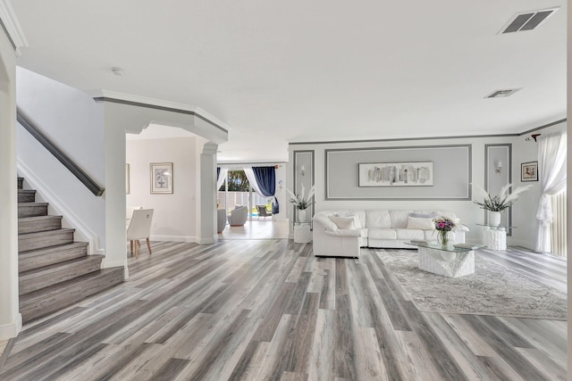 living room with ornate columns, ornamental molding, and light wood-type flooring