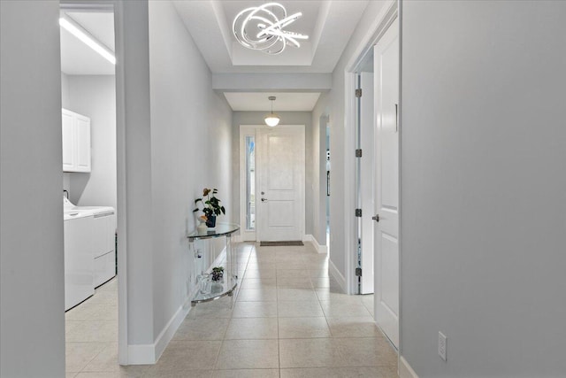 entryway with baseboards, an inviting chandelier, light tile patterned flooring, and washer and clothes dryer