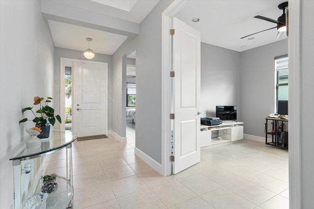 foyer featuring a wealth of natural light, baseboards, light tile patterned flooring, and a ceiling fan