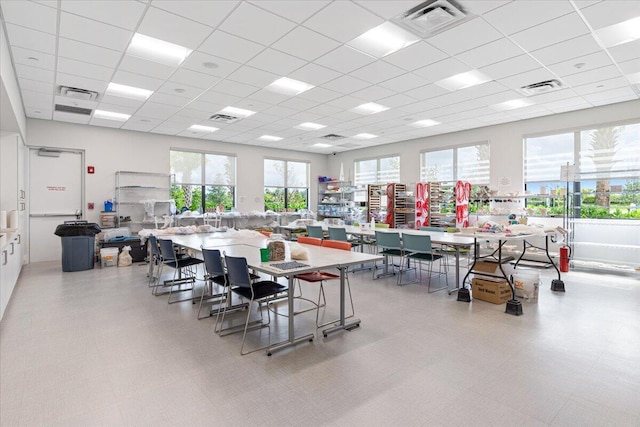 dining space with light floors, visible vents, and a drop ceiling