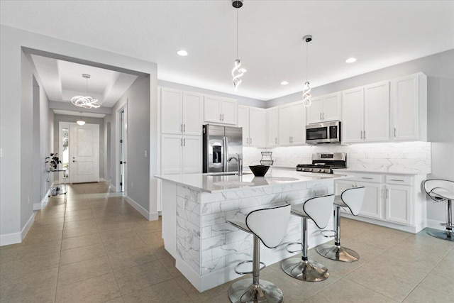 kitchen with a breakfast bar area, white cabinets, pendant lighting, and appliances with stainless steel finishes