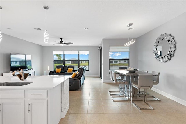 kitchen featuring white cabinets, sink, hanging light fixtures, ceiling fan, and light tile patterned floors