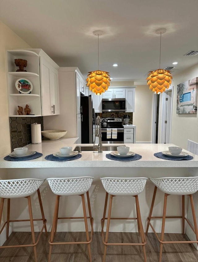 kitchen with stainless steel appliances, hanging light fixtures, a kitchen bar, and white cabinetry