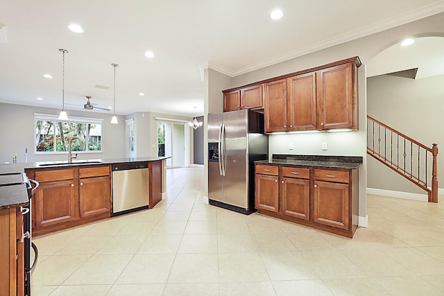 kitchen featuring decorative light fixtures, dark stone countertops, light tile patterned floors, ornamental molding, and stainless steel appliances