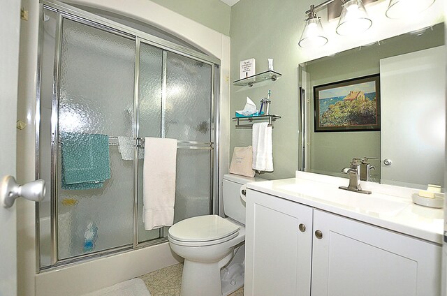 bathroom featuring vanity, a shower with shower door, toilet, and tile patterned floors