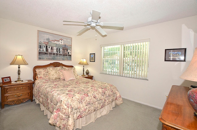 carpeted bedroom with ceiling fan and a textured ceiling