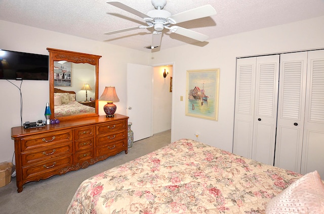 bedroom featuring a textured ceiling, light carpet, ceiling fan, and a closet