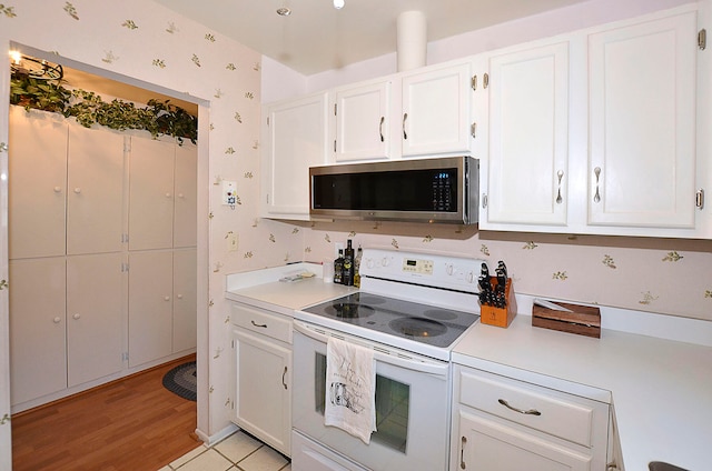 kitchen with white cabinetry, white electric range oven, and light hardwood / wood-style flooring