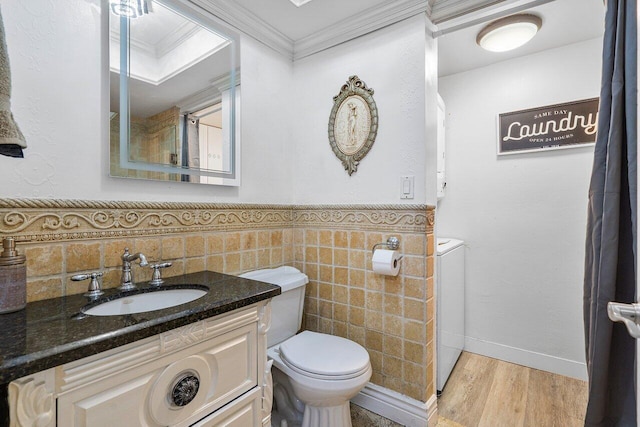 bathroom featuring crown molding, toilet, tile walls, wood-type flooring, and washer / clothes dryer