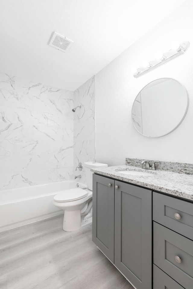 full bathroom featuring tiled shower / bath combo, vanity, toilet, and hardwood / wood-style flooring