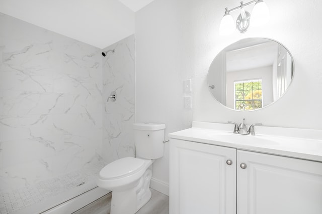 bathroom featuring a tile shower, hardwood / wood-style floors, vanity, and toilet