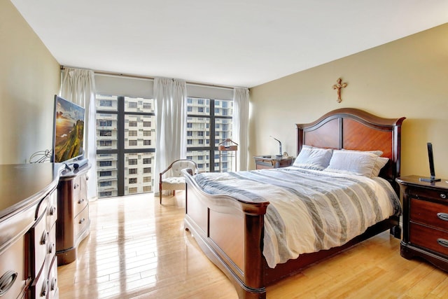 bedroom with expansive windows and light hardwood / wood-style flooring