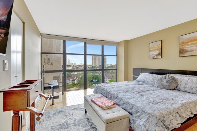 bedroom with expansive windows, light hardwood / wood-style flooring, and multiple windows