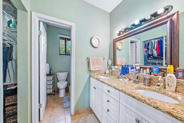 bathroom featuring vanity, toilet, a textured ceiling, and tile patterned floors