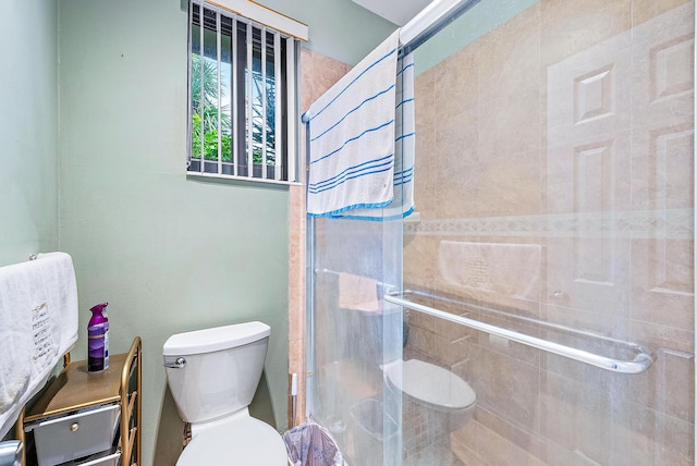 bathroom featuring toilet and a shower with door