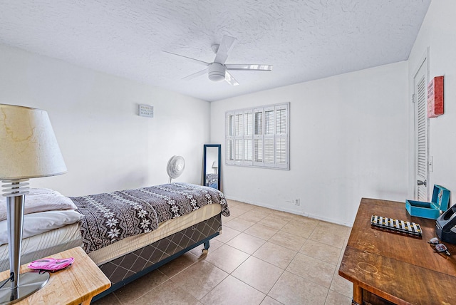 bedroom with tile patterned floors, ceiling fan, and a textured ceiling