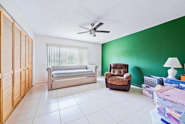 living area featuring ceiling fan, a textured ceiling, and light tile patterned floors