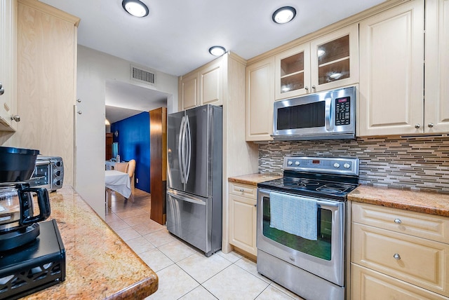 kitchen featuring light stone countertops, light tile patterned flooring, appliances with stainless steel finishes, and tasteful backsplash