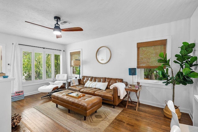 living room featuring ceiling fan, dark wood-type flooring, and a textured ceiling