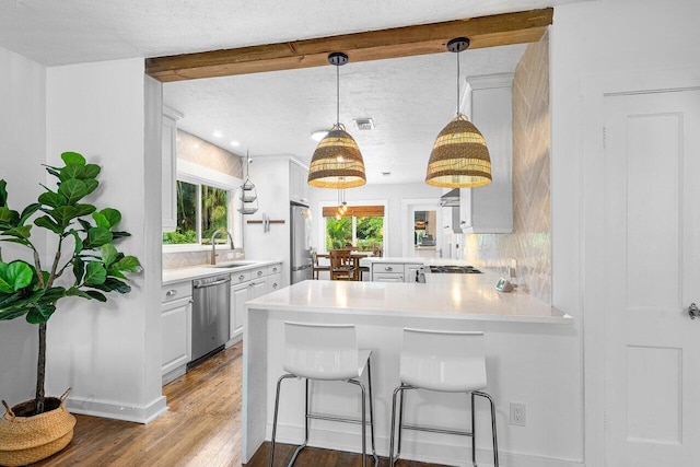 kitchen with kitchen peninsula, stainless steel appliances, dark wood-type flooring, sink, and a breakfast bar area