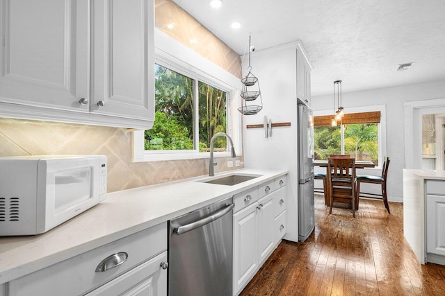 kitchen featuring white cabinetry, dishwasher, decorative light fixtures, and sink