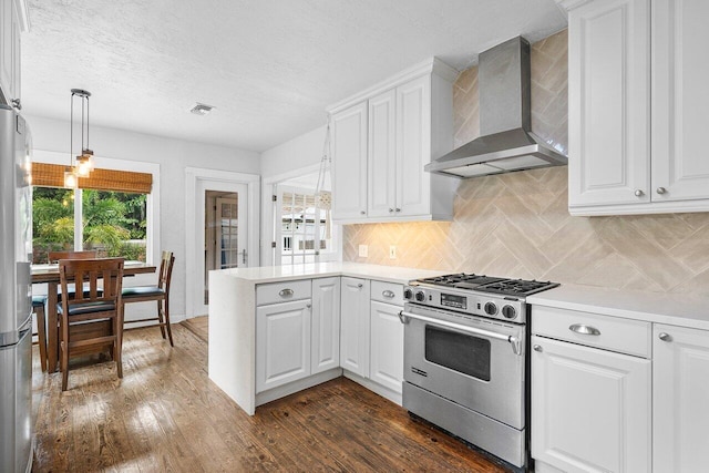 kitchen with white cabinets, wall chimney range hood, high end stainless steel range, decorative light fixtures, and dark hardwood / wood-style flooring