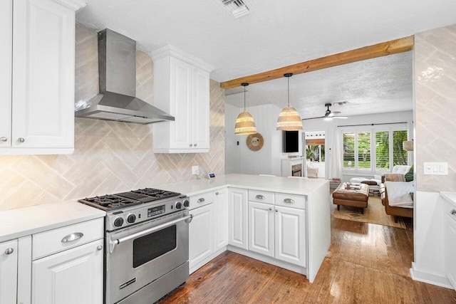 kitchen featuring white cabinetry, dark wood-type flooring, wall chimney range hood, kitchen peninsula, and stainless steel stove