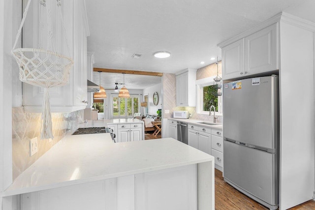 kitchen with kitchen peninsula, appliances with stainless steel finishes, white cabinets, and sink