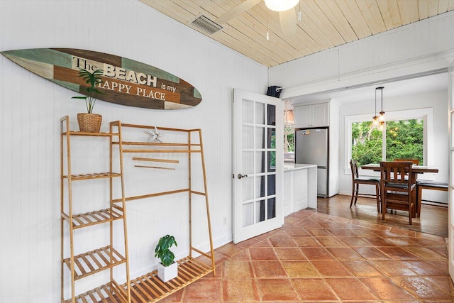 interior space with tile patterned floors, wood walls, ceiling fan, and wood ceiling