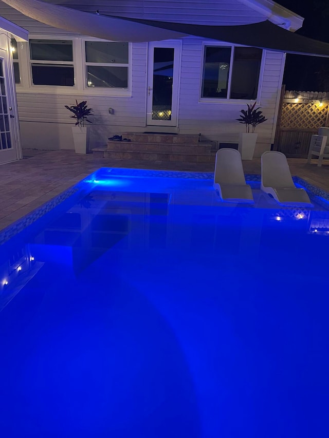 pool at twilight featuring a patio area