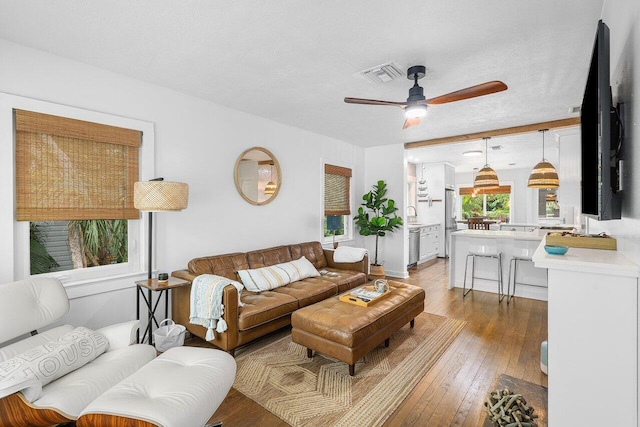 living room with a textured ceiling, light hardwood / wood-style floors, ceiling fan, and sink