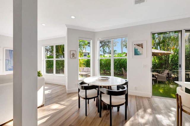 dining area with ornamental molding and light wood-type flooring