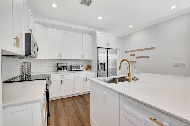 kitchen with light stone countertops, sink, stainless steel appliances, white cabinets, and light hardwood / wood-style flooring