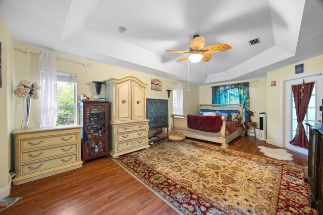 bedroom featuring a tray ceiling, ceiling fan, and dark wood-type flooring