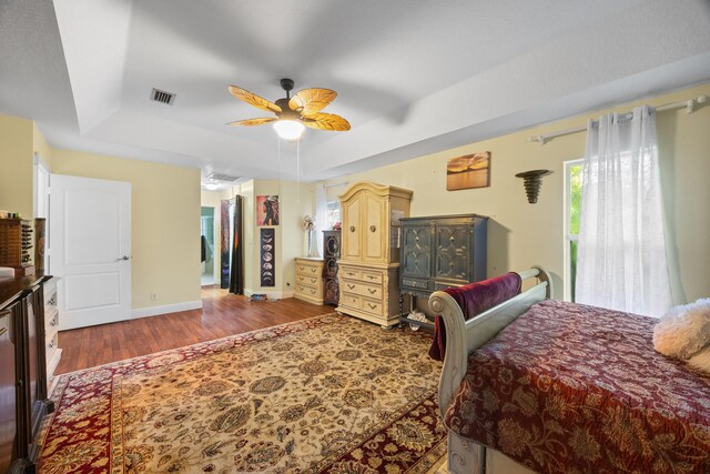 bedroom featuring ceiling fan, hardwood / wood-style flooring, and a raised ceiling