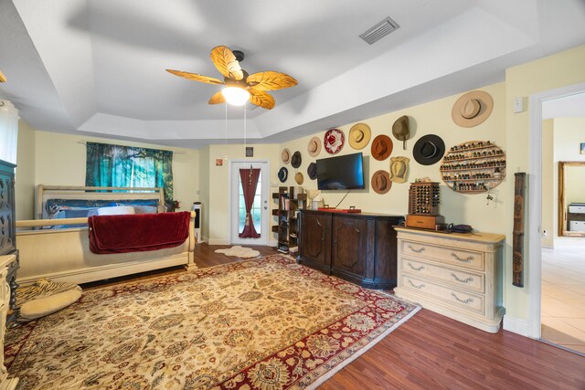 bedroom featuring hardwood / wood-style floors, a tray ceiling, and ceiling fan