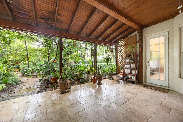 unfurnished sunroom with vaulted ceiling with beams, plenty of natural light, and wooden ceiling