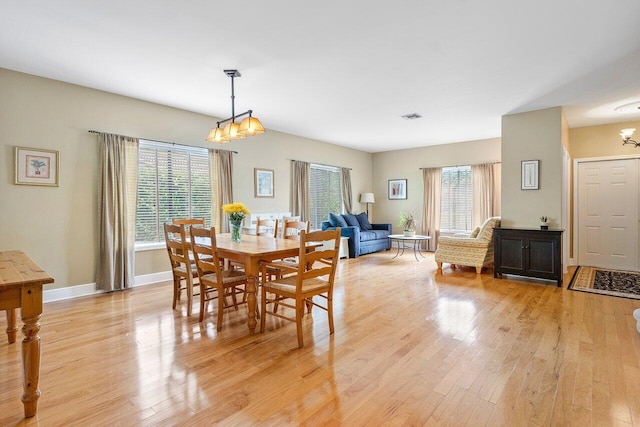 dining space featuring light hardwood / wood-style floors, a notable chandelier, and plenty of natural light