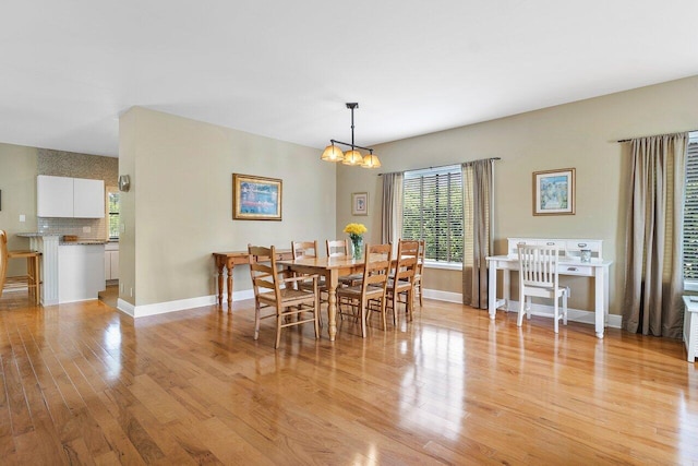 dining space with light hardwood / wood-style floors and a chandelier