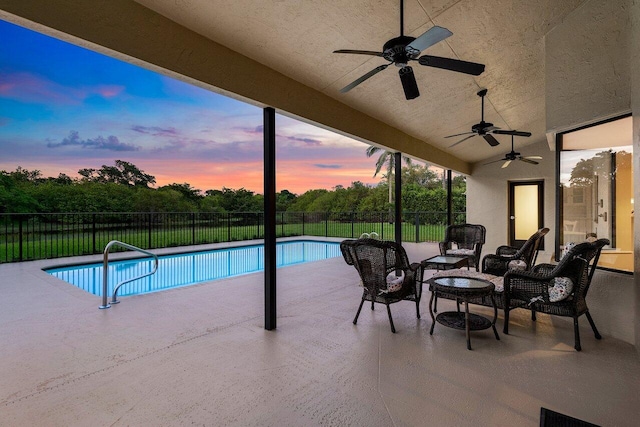 pool at dusk featuring a patio area and ceiling fan