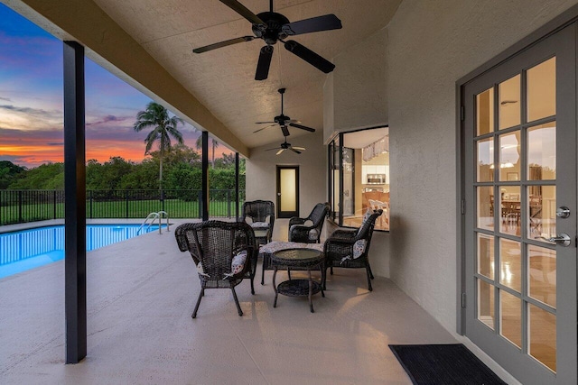 pool at dusk with a patio, an outdoor living space, and ceiling fan