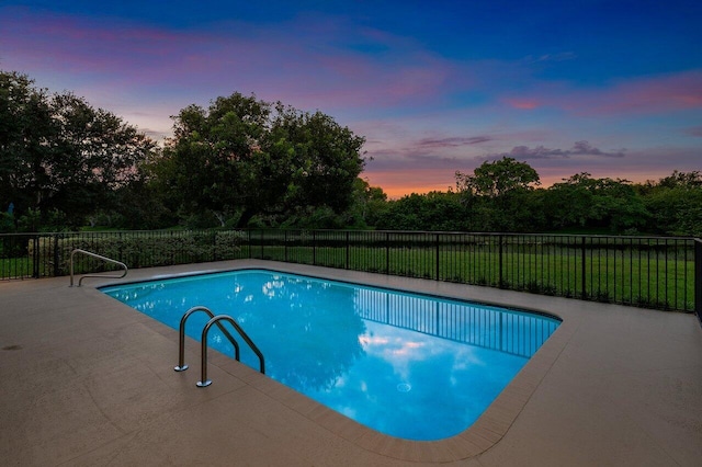 pool at dusk with a yard and a patio area