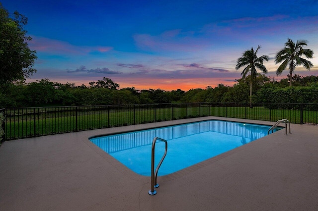 pool at dusk featuring a yard and a patio area